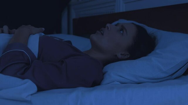 Bad dream. Awakened woman lying in bed having nightmare