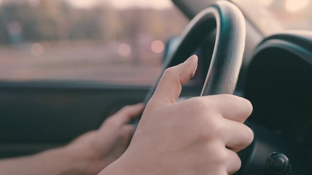 Impatient Driver's Drumbeat: Close-Up of Thumbs Tapping on Steering Wheel | Shallow Focus Captures Restless Hands in City Traffic | Side View with Blurred Left Hand and Wheel