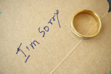 Note with the sorry word next to a wedding ring.