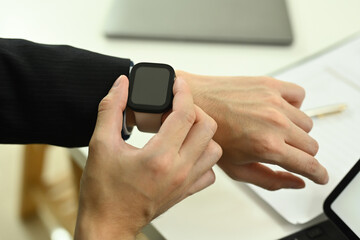 Close up young businessman in formal wear checking time on smartwatch. Time management concept