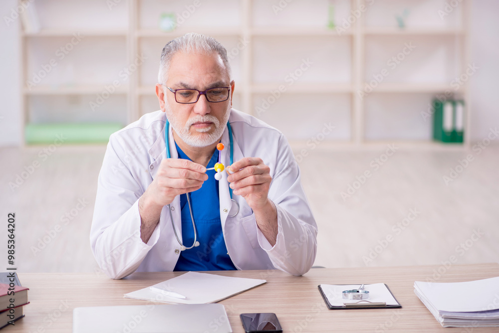 Wall mural old male doctor working in the clinic