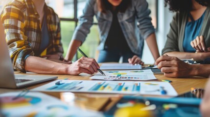 Three women are sitting around a table with papers and a pen