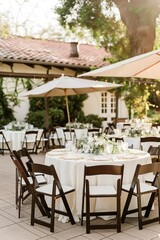 Fototapeta premium Outdoor wedding venue with white tables surrounded by chairs. Beautiful scenery with green plants and natural surroundings. Elegant arrangement of chairs and tables for a romantic marriage ceremony.