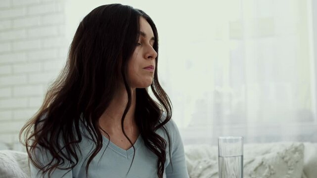 Depression treatment concept. Upset woman taking antidepressant drug or tranquilizer at home, tracking shot, slow motion