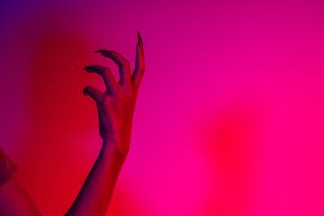 Obraz premium A terrifying witch's hand with long red nails, resembling a demon or vampire. Its gnarled appearance hints at monstrous origins, resembling an alien or ghostly entity,with zombie-like decayed skin.