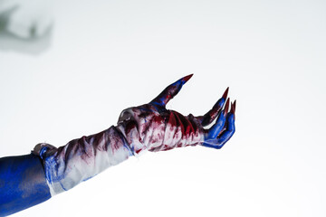 A blue witch hand with red nails, wrapped in a blood-stained bandage against a white background....