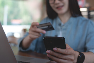 Smiling young asian woman using mobile phone and credit card for mobile banking, digital payment via mobile app. User using smartphone for online shopping and internet payment