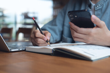Event planner timetable agenda plan on year 2025 schedule event. Business woman checking planner on mobile phone, taking note on calendar desk on office table. Calendar event plan, work planning