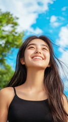 Smiling Young Woman in a Natural Setting with Blue Sky and Greenery
