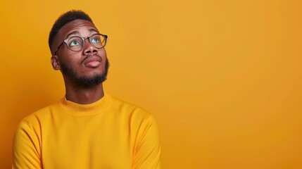 Obraz premium black man in glasses looking up at copy space on yellow background