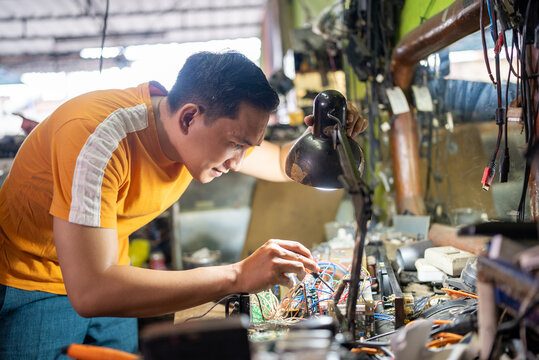 technician working on testing electronics using a screwdriver under the light of a workbench