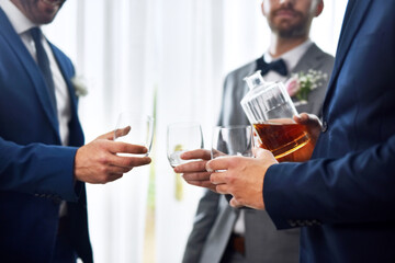 Cheers, wedding and groomsmen with alcohol drink for celebration of romantic event together. Hands, commitment and best friends with shot of whiskey for toast and getting ready for marriage ceremony.