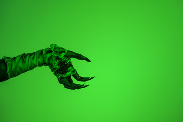 A bloodied witch hand wrapped in bandages, set against a green fire background. This demonic hand...