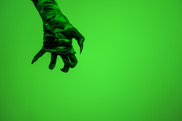 A bloodied witch hand wrapped in bandages, set against a green fire background. This demonic hand...