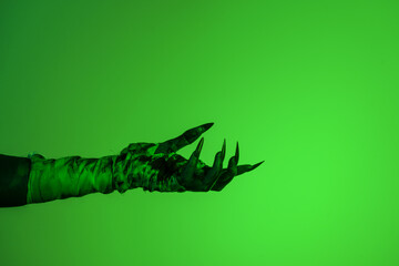 A bloodied witch hand wrapped in bandages, set against a green fire background. This demonic hand blends elements of vampires,aliens, and ghosts, evoking a spooky, monstrous feel perfect Halloween