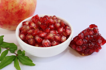 Juicy red pomegranate seeds in a cup placed between ripe fruits and seeds attached to the peel along with leaves, on a white background.

ไอคอนยืนยันโดยชุมชน