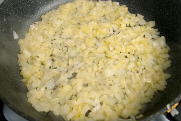 Closeup cooking frying chopped onions and garlic in frying pan on kitchen gas oven. Culinary techniques, homemade preparing healthy meal, cook food dish, cuisine, seasoning for meal taste.