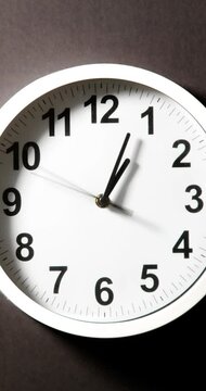 Close up to wall clock, with running time pointer. Sun and sky reflecting on clock face time passing by. Vertical time lapse on a modern white Clock on blur background. Wall clock show running time. 