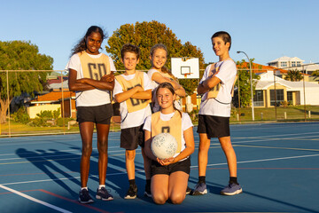 five members of a children's mixed netball team posing for a photo