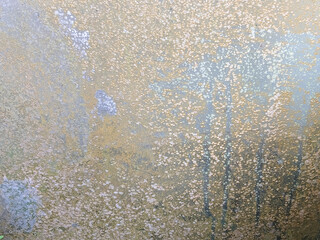 Close-up of dirty glass with a mixture of brown and gray. The surface is uneven and has a rough texture, almost speckled.