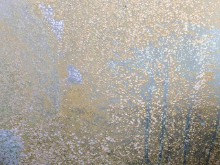 Close-up of dirty glass with a mixture of brown and gray. The surface is uneven and has a rough texture, almost speckled.