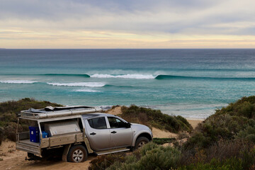 A silver ute bogged in sand on coastal path by seaside