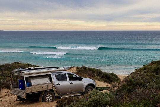 A silver ute bogged in sand on coastal path by seaside