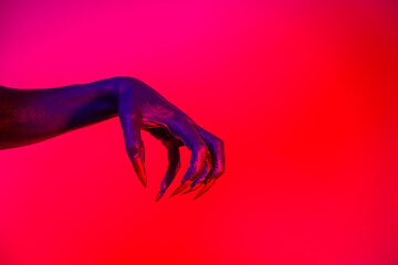 A witch hand with long nails appears against a red fire background, evoking a demonic, monstrous...