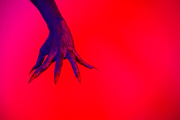 A witch hand with long nails appears against a red fire background, evoking a demonic, monstrous presence. Blending vampire, alien, ghost, and zombie elements, it perfectly embodies Halloween