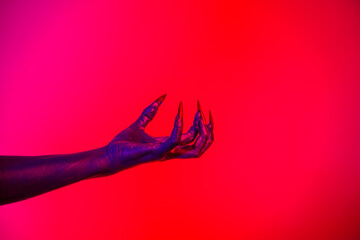 A witch hand with long nails appears against a red fire background, evoking a demonic, monstrous presence. Blending vampire, alien, ghost, and zombie elements, it perfectly embodies Halloween