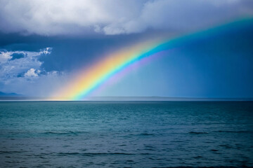 Rainbow with clouds on horizon with ocean