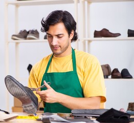 Young man repairing shoes in workshop