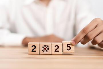 Businessman hand flipping wooden cube from 2024 to 2025. New year resolution, goal, plan, and...