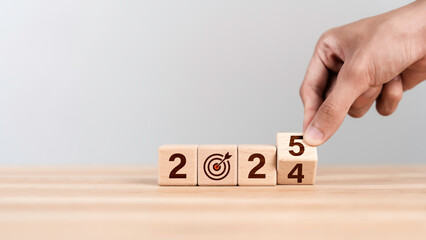 Businessman hand flipping wooden cube from 2024 to 2025. New year resolution, goal, plan, and...