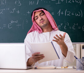 Arab teacher in front of chalkboard