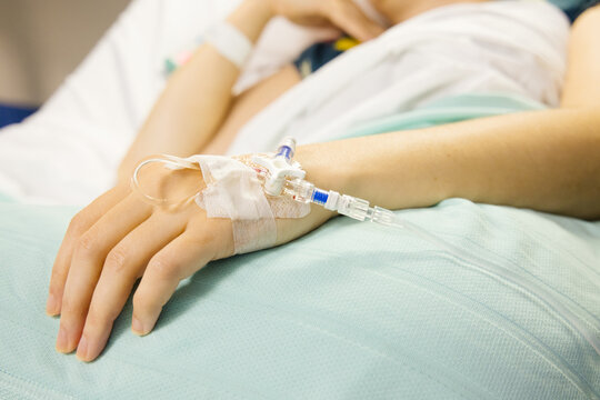 A cannula in the left wrist of a female patient lying on a bed