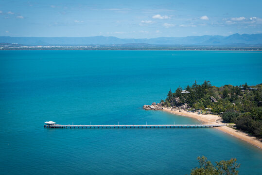 Aerial shot of a coastal landscape with a long pier