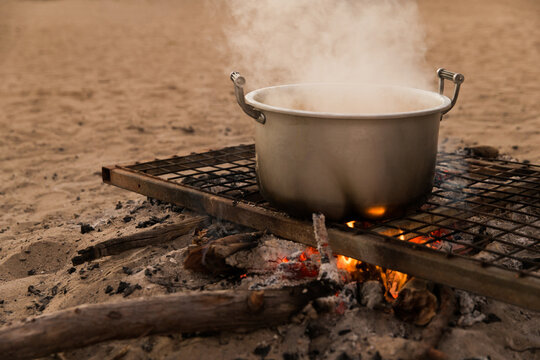 A metal pot on a grill over an open fire.