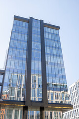 A tall building with a lot of windows and a reflection of the sky