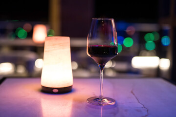 red wine in glass of rooftop bar at night with bokeh city light