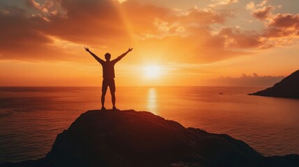 A man stands on a rock overlooking the ocean at sunset