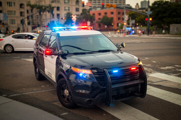 A police car with emergency lights on stopped in an urban environment