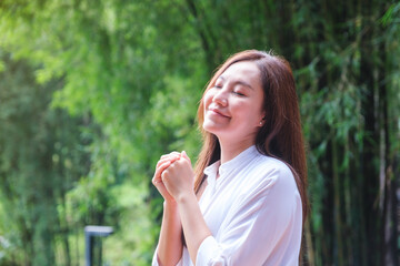 Fototapeta premium Portrait image of a young woman with closed eyes enjoying and relaxing with nature