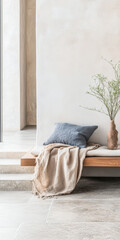 Cozy indoor corner with modern seating, soft blanket, and minimalist decor in a bright, airy space during daylight