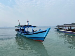 Naklejka premium Bandar Lampung, Indonesia - September 1st 2024: Fishing boats are parked on the seashore in the afternoon with a cloudy sky in the background