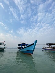 Fototapeta premium Bandar Lampung, Indonesia - September 1st 2024: Fishing boats are parked on the seashore in the afternoon with a cloudy sky in the background