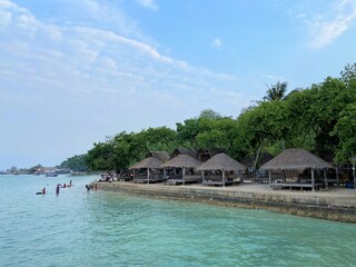 Lampung, Indonesia - September 1st 2024: Gazebo atmosphere on the edge of Mutun Beach in the afternoon with light brown sand and a cloudy sky as a background