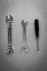 Home tools for repair and maintenance of equipment, screwdriver, metal wrench on cardboard box background. Black and white vertical photo from top to bottom.