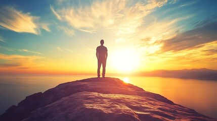 Obraz premium Man Silhouette Standing on Mountain Peak at Sunset
