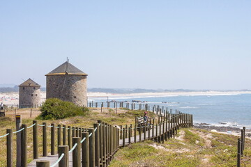 Coastal Pathway with Historic Windmills and Ocean View on a Sunny Day